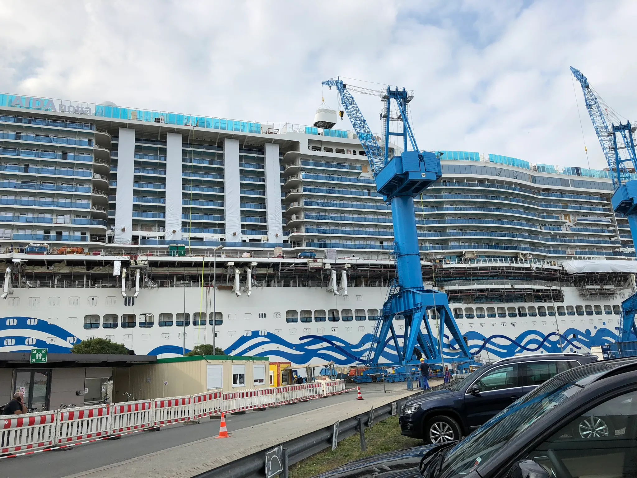 Die AIDAnova im Endausbau an der Ausrüstungspier der Meyer Werft, davor Kräne im Einsatz