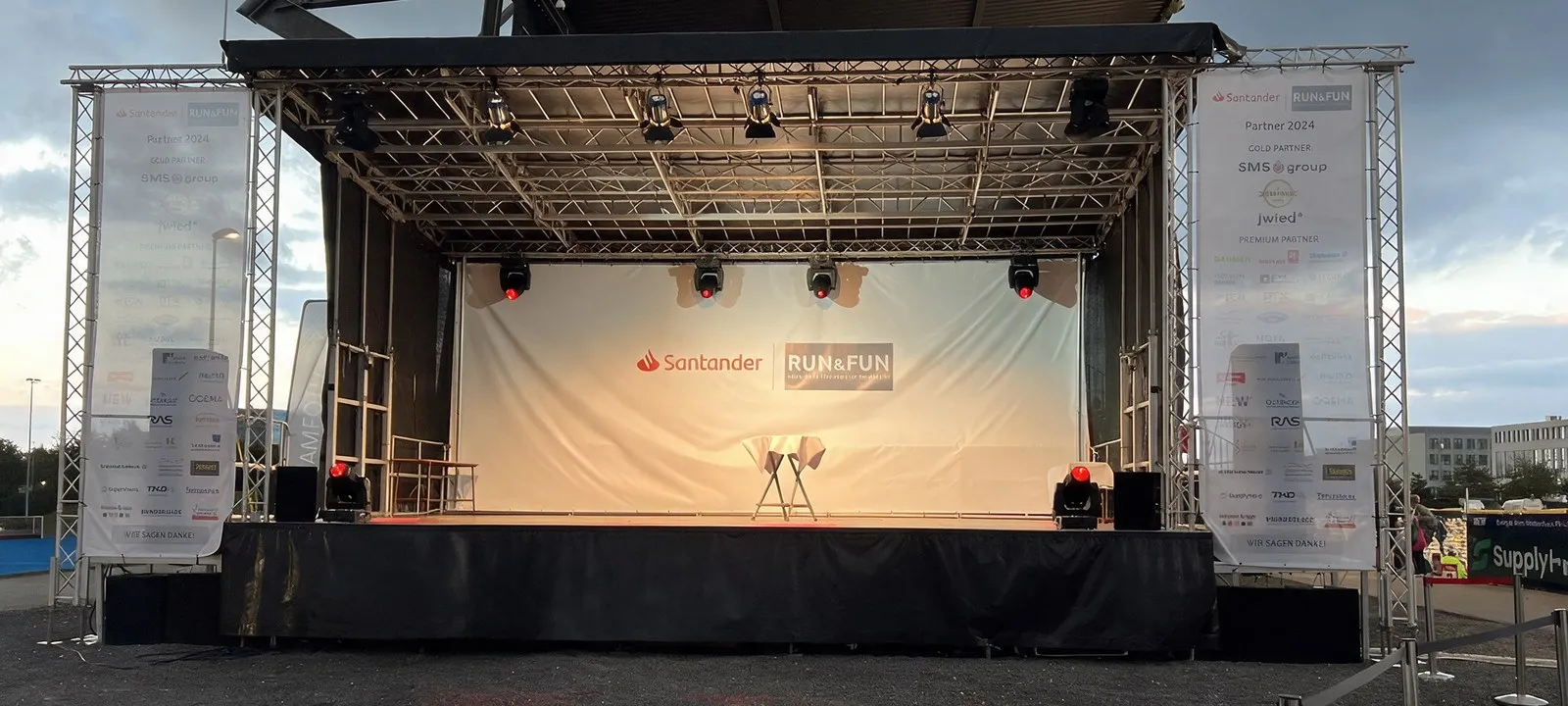 Unsere 12-Meter-Bühne bei Dämmerung mit Moving-Heads und Sponsorenwänden