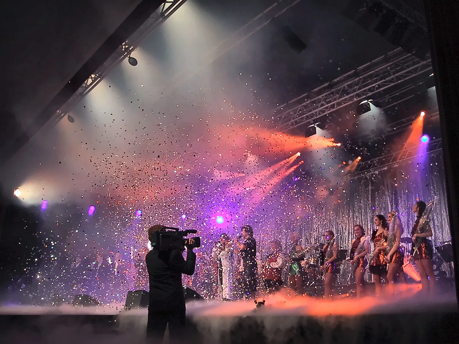 Konfettiregen über der Bühne beim Finale, davor die Silhouette des Kameramanns der Live-Produktion