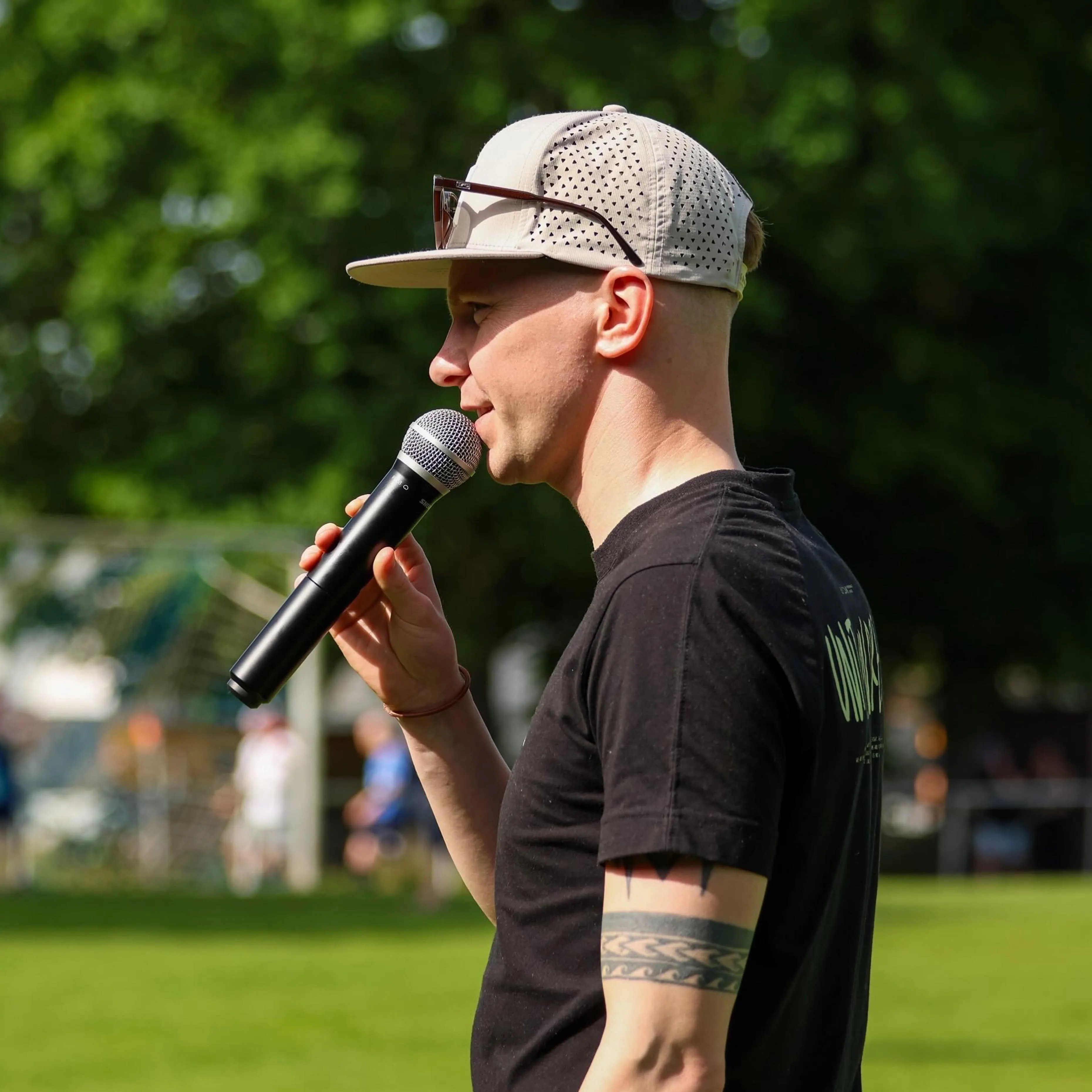 Sportmoderator Janik Broszeit im Profil mit Mikrofon am Sportplatz